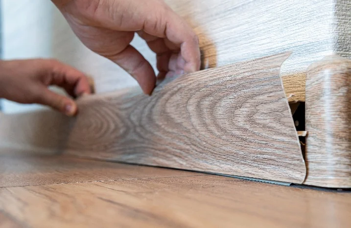 Person bringt Fußleiste an